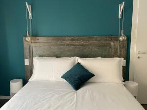布雷西亚Ca'Sazen Trilo 19的一张带白色枕头和蓝色墙壁的床