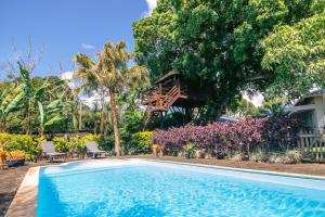 ArgyTree Lodge Mauritius Villa的一座游泳池,后面是树屋
