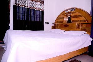 德奥加尔SHIVAY Guest House的卧室配有一张白色大床和木制床头板