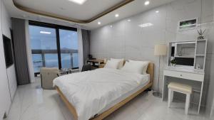 釜山Emotional cafe street Stay的一间卧室配有一张大床、一张桌子和一个窗户。