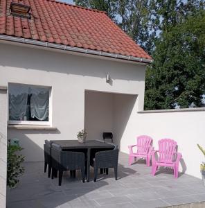 GuempsL'essentiel的庭院配有黑色桌子和粉红色椅子