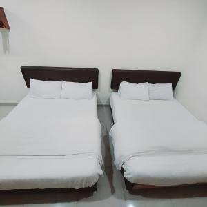 怡保Hotel Lean Fatt的两张带白色床单的床铺,彼此相邻