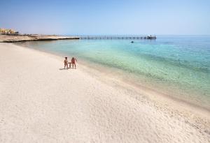 阿布达巴莫林海滨和睦度假酒店的两人在海边的海滩上散步