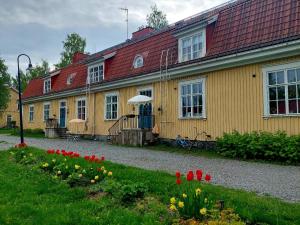 瓦尔考斯Nostalginen residenssi Taika的黄色的房子,前面有红色的屋顶和鲜花
