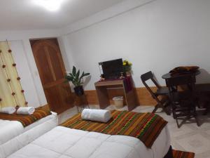 库斯科Incas Town Inn的客厅配有一张床和一张书桌及电视