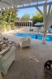 普罗塔拉斯Riverland beach villa的庭院设有游泳池、椅子和桌子。