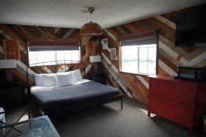 亨廷顿海滩亨廷顿冲浪酒店的一间卧室配有一张床、一个梳妆台和两个窗户。