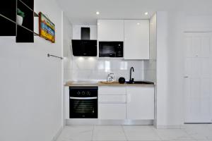 帕莱索海滩帕拉迪斯奢华公寓的厨房配有白色橱柜和黑烤箱。