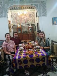 非斯Fes Antique Hostel的一群人坐在桌子旁吃着食物