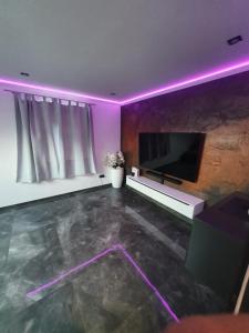 帕德博恩Los Angeles Apartment的客厅配有平面电视和紫色灯