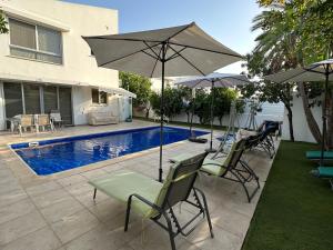 拉纳卡Villa Victoria的游泳池旁的天井配有椅子和遮阳伞。