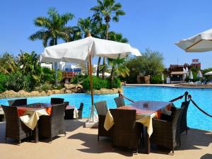 沙姆沙伊赫Apartments for rent in Delta Sharm Resort的游泳池旁带遮阳伞的桌子