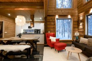 普哈圣山Charming log house - Lumous B - Pyhätunturi - Finland的厨房以及带桌子和红色椅子的客厅。