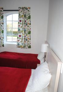 哈尔姆斯塔德Wapnö Gårdshotell的一间卧室设有红色的床和窗户。
