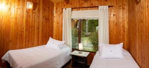 普孔Cabañas Estero Loncotraro的一间卧室设有两张床和窗户。