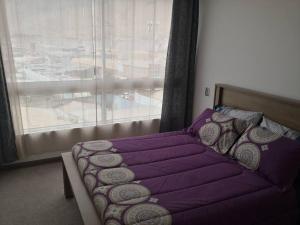 伊基克Sensacional Departamento cerca Zofri 2 Habitaciones 2 Baños Iquique的一间卧室配有一张带紫色床单的床和窗户。