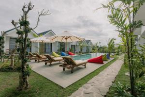 坎古Sari Uma Canggu By Hospitality Bali的别墅内的游泳池配有长椅和遮阳伞