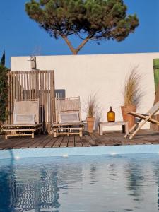 卡瓦利亚尔Casa Atlântico Carvalhal Comporta, apartamento piscina aquecida的游泳池畔的两把椅子和一张桌子