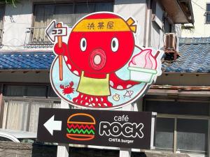 南知多Support Inn Minami-Chita Annex Hamachaya的上面有红怪物的咖啡岩石标志