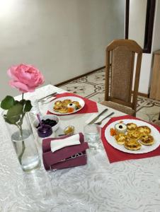 LyubintsyВілла Сади Єви的一张桌子,上面放着两盘食物和一朵粉红色玫瑰
