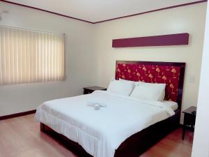 安吉利斯Jun and Helen Hotel and Restaurant的一间卧室配有一张白色大床和红色床头板
