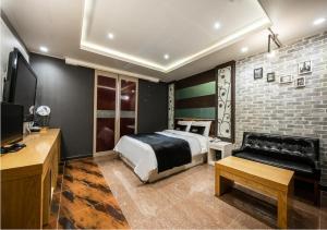 蔚山Hotel Kobos的一间卧室配有一张床、一张沙发和一台电视。