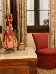 大加那利岛拉斯帕尔马斯Casa Colonial El Indiano的坐在椅子旁边的桌子上的红色花瓶