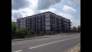 波兹南Apartament Nadwarciański的道路一侧的白色大建筑