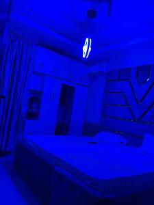 Meerah apartments & Hotels的一间暗室,配有两张床和蓝色的灯光