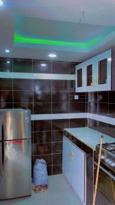Meerah apartments & Hotels的厨房配有不锈钢冰箱和黑色瓷砖墙壁