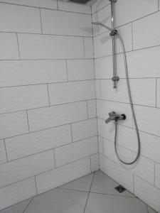 帕皮提Chalet Ohana, airport family house的白色瓷砖浴室内带软管的淋浴