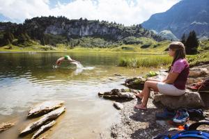 施勒肯Hus23的坐在湖边看男人游泳的女人
