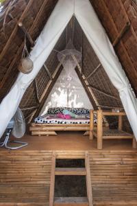 马拉帕斯加Georgia's Neverland Hostel的茅草屋顶帐篷内的一张床