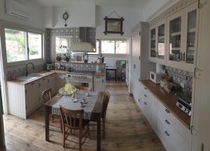 Lefke-KaradağDervise Mehmet Guest House的一间带桌椅的厨房和一间带白色橱柜的厨房