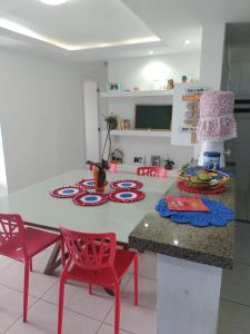 福塔莱萨Quartos - Cíntia的厨房配有桌子、两把红色椅子和一张桌子