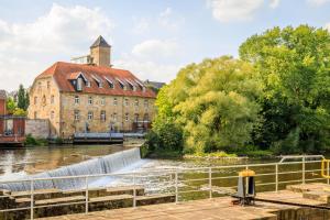 赖讷Cascada Central Hotel Rheine的一座古老的建筑,毗邻一条有瀑布的河流