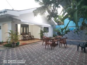 尼甘布Bee Cottage Negombo的房屋前设有带桌椅的天井。