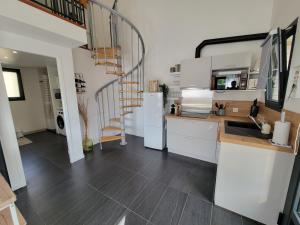 安德诺莱斯贝恩Les Cabanes de l'Airial Ecume的厨房配有白色橱柜和螺旋楼梯