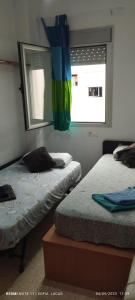 格拉纳达Disfruta Granada,incluso con tu mascota Parking的一间卧室设有两张床和一个带彩虹旗的窗户。