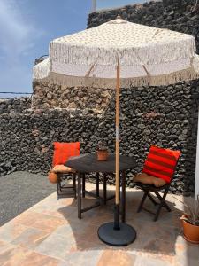 Caleta de CaballoCasa Cabrera - 2 apartamentos con vistas al mar的一张桌子和两把椅子及雨伞