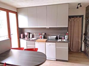 维拉尔-德朗Joli studio & Belle Vue + wifi的厨房配有白色橱柜和红色椅子的桌子