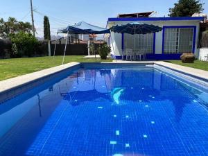 瓦兹特佩克Casa en Oaxtepec的一个带遮阳伞和房子的蓝色游泳池