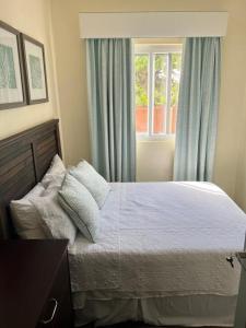 ChoiseulKaye Devo的一间卧室配有一张带蓝色窗帘的床和一扇窗户