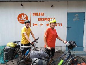 阿里巴格Awaara Backpackers Hostel, Alibag的两个头盔上的人站在自行车旁