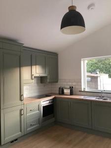 基拉尼Rose Cottage的厨房配有绿色橱柜、水槽和窗户