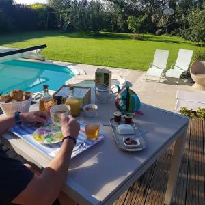 MathieuGrande Chambre entre caen et la mer chambre terrasse jardin et piscine的坐在桌子上的人,带上一盘食物