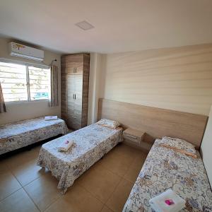 伊瓜苏港Taroba Apart的带三张床和窗户的客房