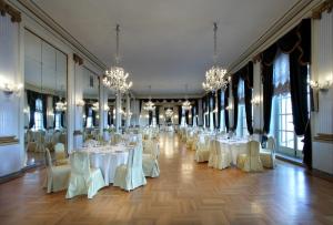 那不勒斯艾克塞尔西亚欧洲之星酒店的宴会厅配有白色的桌椅和吊灯