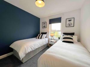 哈特菲尔德Beautiful Hatfield 2 Bedroom Apartment FREE Gated Parking - Modern Stylish - Business Park, Hertforshire University, St Albans, Welwyn Garden City, Luton Airport, Harry Potter Studio Tour的一间卧室设有两张床和蓝色的墙壁