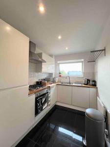 哈特菲尔德Beautiful Hatfield 2 Bedroom Apartment FREE Gated Parking - Modern Stylish - Business Park, Hertforshire University, St Albans, Welwyn Garden City, Luton Airport, Harry Potter Studio Tour的白色的厨房设有水槽和炉灶。